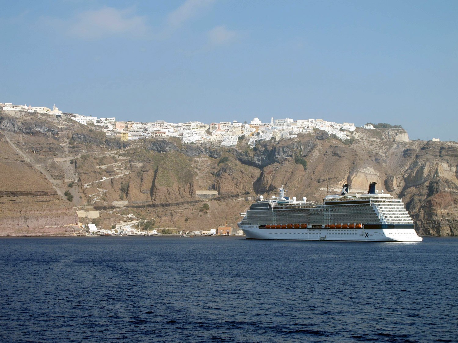 Тысячи путешественников прибывают на круизных корабляхна Санторини. Захватывающий вид на Фиру.